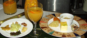 奄美の特産を用いたオードブル: 青パパイヤのマリネや漬物（左皿）、たんかんサングリア（グラス）、フル（葉ニンニク）のオムレツ（右皿）や茹で煮トビシャ（貝）など<br />
